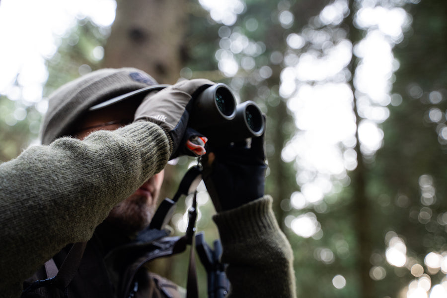 Stalker glassing woodland with binoculars
