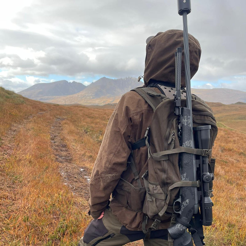 Stalker with rifle looking over open hill ground